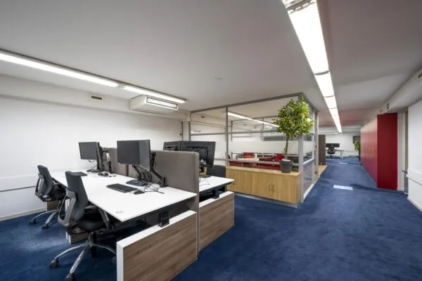 Modern kantoorinterieur aan de Prins Hendrikkade met werkplekken, vergaderruimte en blauwe vloerbedekking.